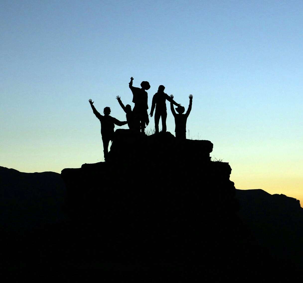 Silhouette di persone che salutano l'alba su una piccola collina