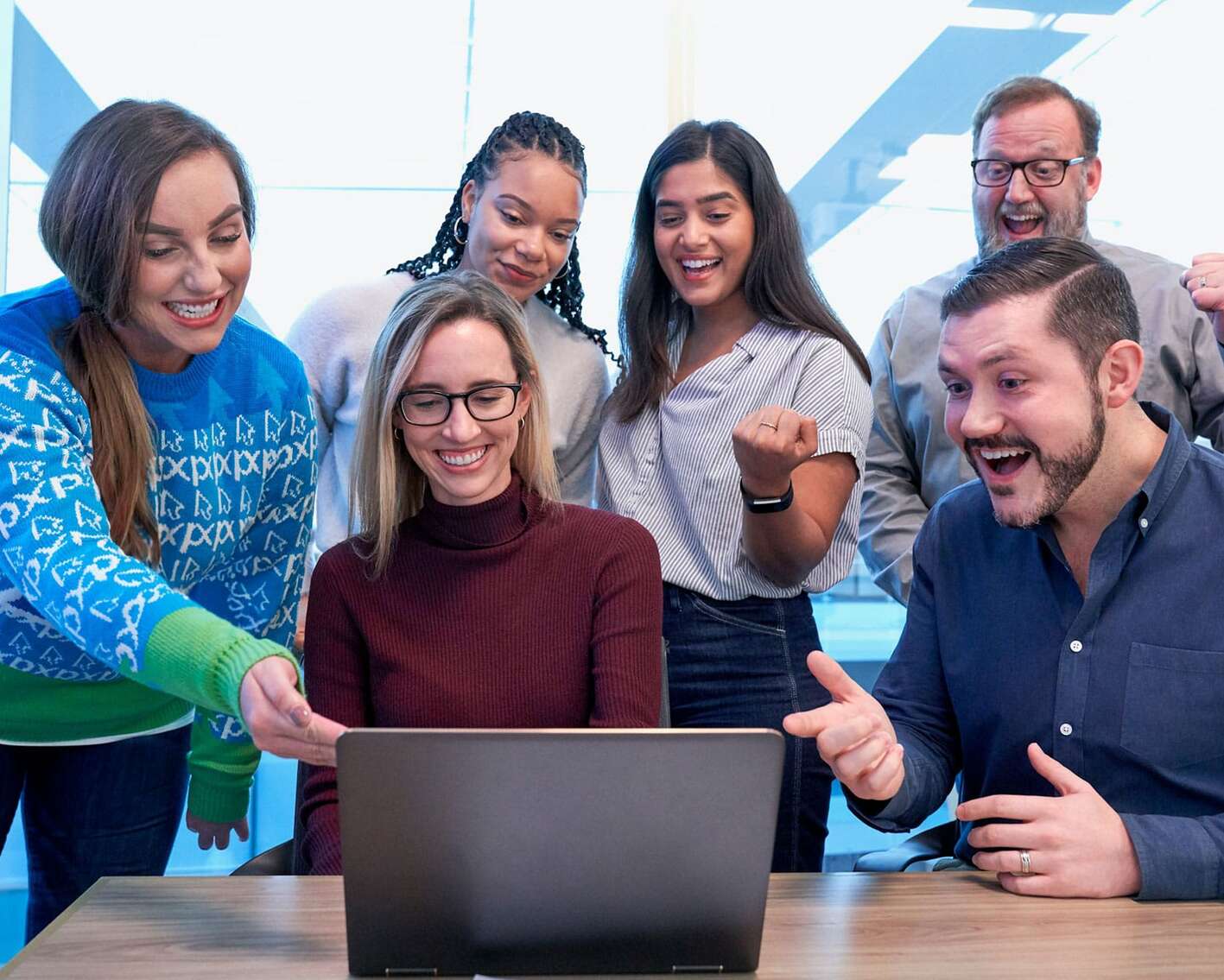 Gruppo di persone sorridenti in un ufficio che osservano lo schermo di un computer